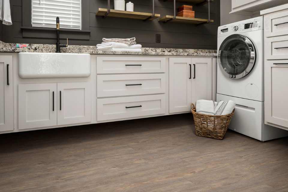 wood look luxury vinyl in modern laundry room with white cabinets and grey shiplap walls